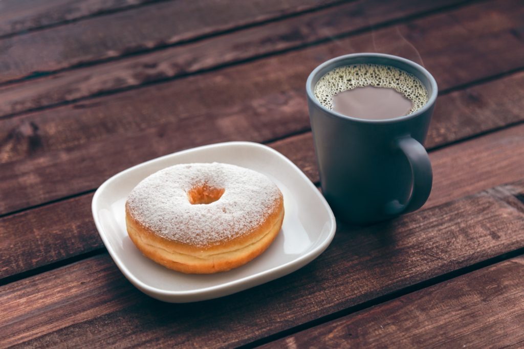 A cup of coffee and powdered sugar doughnut