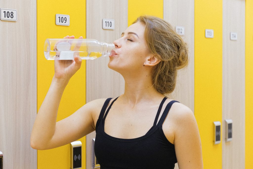 A woman drink a bottle of water after exercising