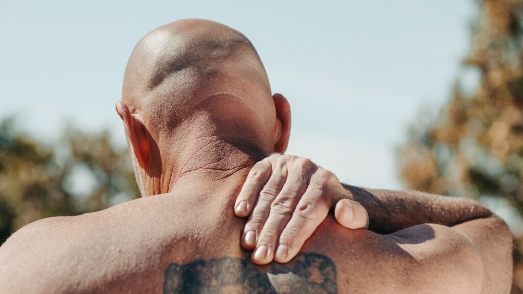 A man holds his neck due to a muscle strain