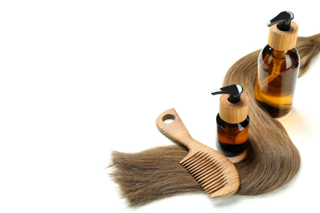 Two bottles of oil for hair treatment, healthy hair, and a comb