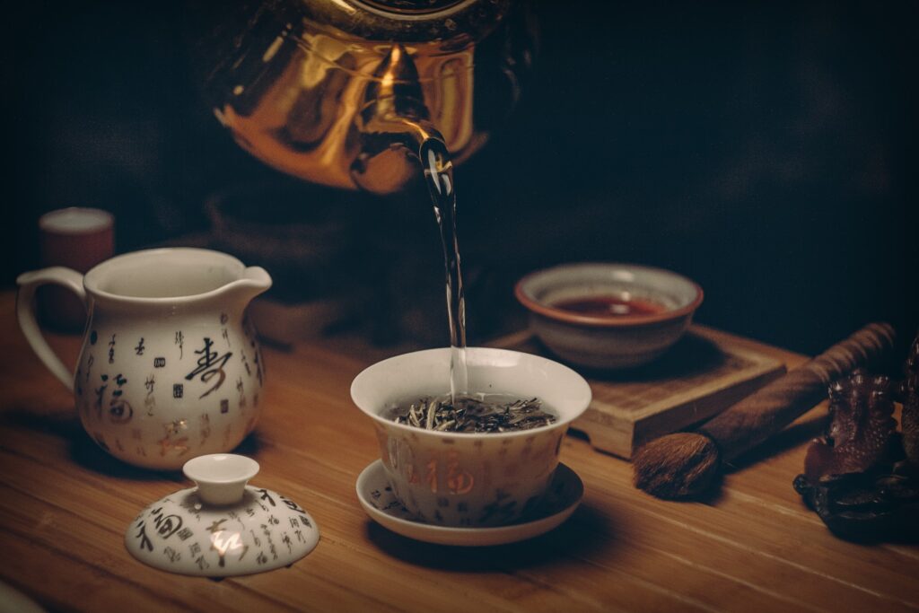 Gold Kettle Pouring Hot Water on Cup of herbal Tea
