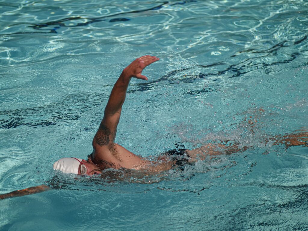 A man with a tattoo on his left arm swimming in the pool