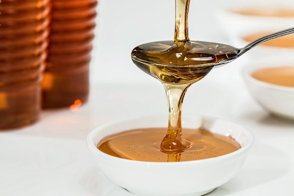 Pouring honey on a teaspoon and white bowl