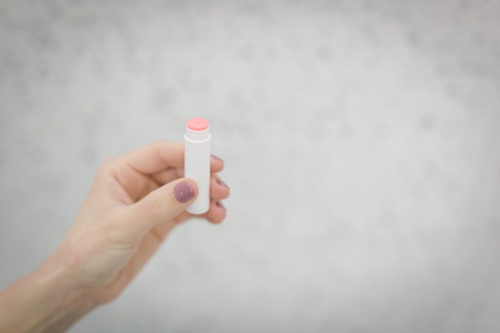 A woman holding a pink lip balm      