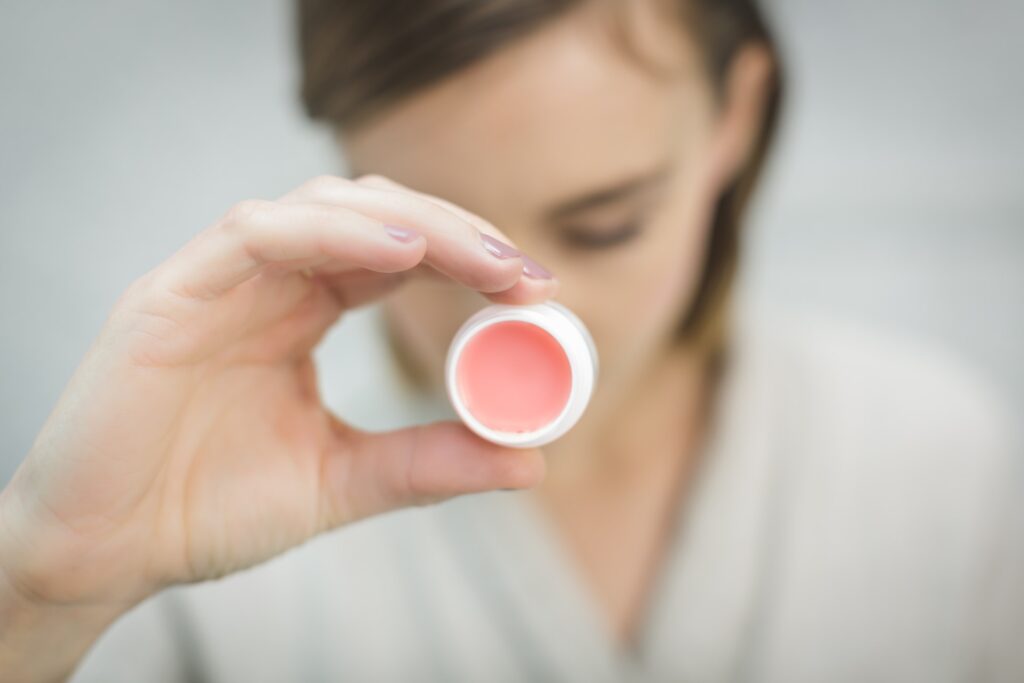 A woman hold a cute pink lip care product